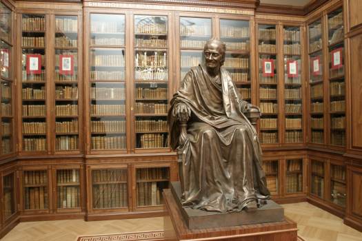 Бронзовая скульптура Вольтера на фоне шкафов с его библиотекой