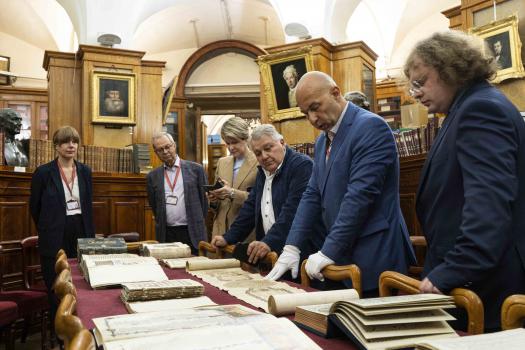 Заместитель заведующего отдела рукописей Михаил Алексеевич Шибаев знакомит высоких гостей со старинными рукописями.